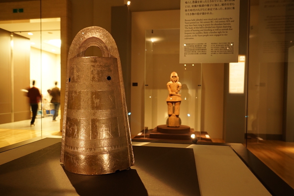 手前：《扁平鈕式銅鐸》弥生時代・前2世紀〜前1世紀、奥：《埴輪 挂甲の武人》古墳時代・6世紀