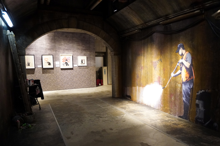 『バンクシーって誰？展』会場風景（東京の様子）。ロンドンのウォータールー駅付近のトンネルにあった《Whitewashing Lascaux(The Cans Festival)》の再現展示。