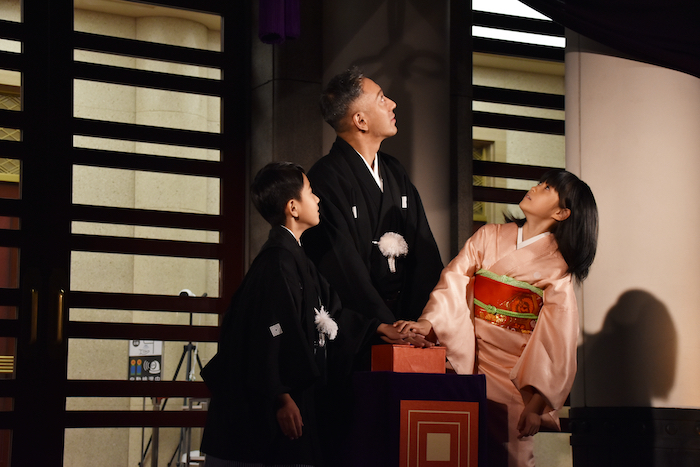 柿色に染まった歌舞伎座を見上げる市川新之助、市川團十郎、市川ぼたん（左から）
