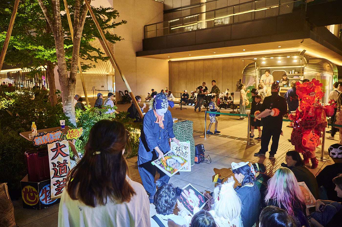 見世物小屋ショーでの一幕。”家族紙芝居の○○一味”による読み聞かせには人だかりが。