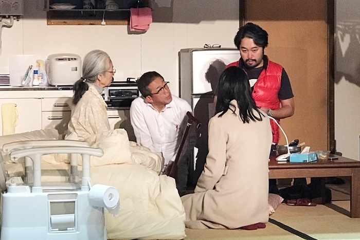 タニノの説明を聞く『笑顔の砦』介護家族チーム。（左から）百元夏繪、たなべ勝也、坂井初音。