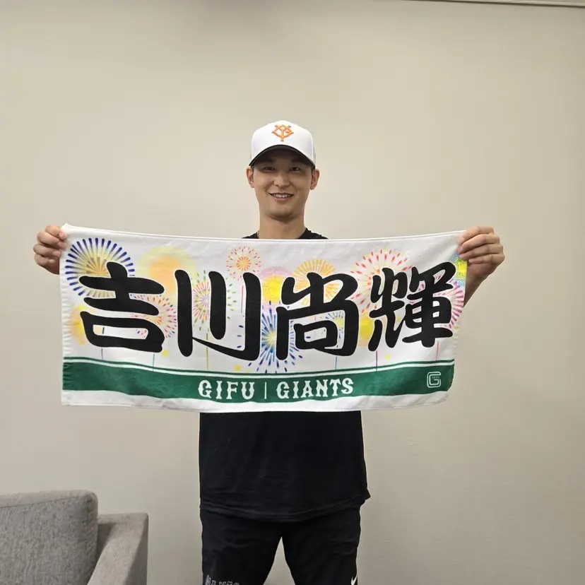 開催記念プレーヤーズフェイスタオルを持つ吉川選手