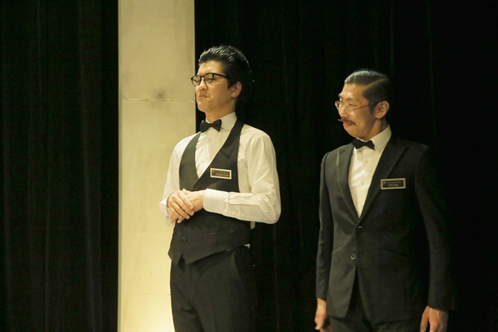 舞台となる高級ホテルの従業員（左／入江拓郎　右／ボブ・マーサム）も、交渉の重要な鍵を握ることに。