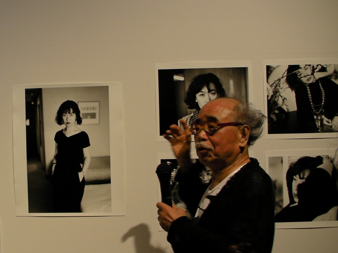 妻・陽子の写真を背景に。左側のポートレイトは遺影に使われた。