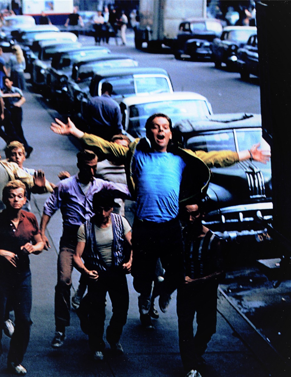『ウエスト・サイド物語』（1961年）から、映画冒頭〈プロローグ〉のリハーサル風景。正面で飛び上がっているのは、ジェット団のリーダー、リフ役のラス・タンブリン