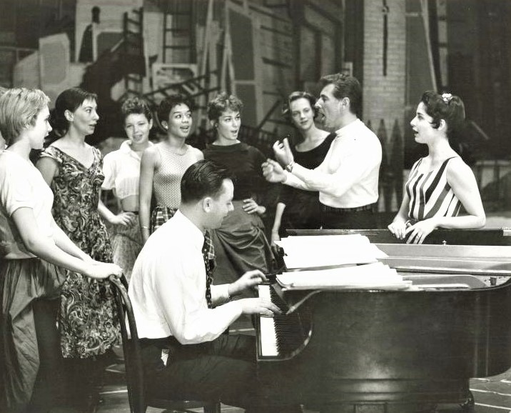 『ウエスト・サイド・ストーリー』初演（1957年）のレッスン風景。右端がマリア役のキャロル・ローレンス、その隣がレナード・バーンスタイン（作曲）、ピアノを弾くのが若き日のソンドハイム。