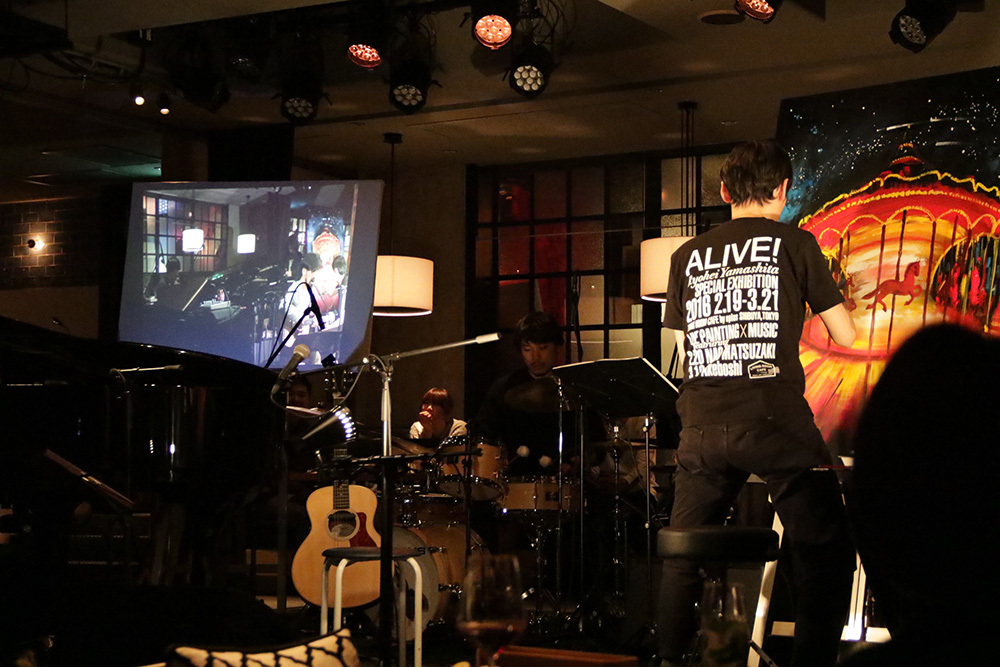ステージ左側に設置されたスクリーンに、直前に行われたライブ映像が投影される