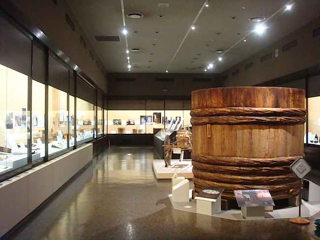 【序章】と【第1章】の展示室中央には、実際に使用されていた豆みその仕込み桶が。高さ・直径ともに六尺（約2m）あり、このひと桶で17万食分もの味噌汁を作ることができるとか