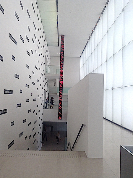 やわらかく外光を採りこむ一面のガラス壁がより美しく。左壁面のジョセフ・コスース《分類学（応用）No.3』と中央のジェニー・ホルツァー《豊田市美術館のためのインスタレーション》は、開館当初からの常設作品