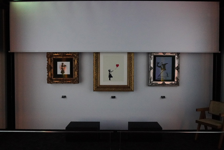 『バンクシー展』会場風景。映像が終わると正面のスクリーンの幕が上がり、満を持して作品が登場。