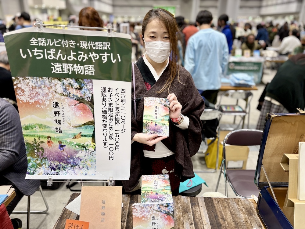 着物姿でブースに立つ「いちばんよみやすい遠野物語」の作者・天叢らいさん（カテゴリはノンフィクション／郷土）。一緒に娘さんも売り子をしていてほっこり。