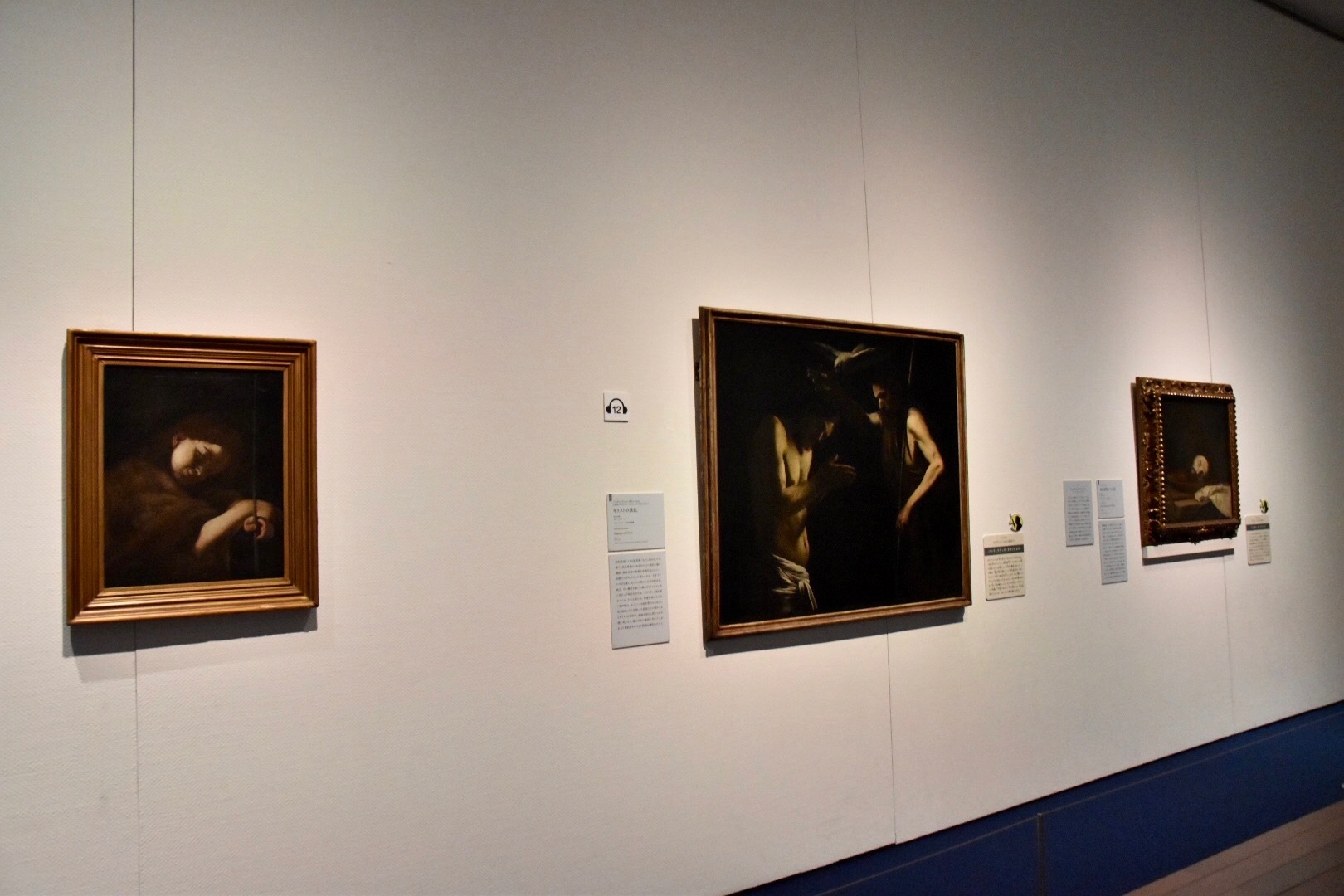 左：バッティステッロ・カラッチョロ（本名ジョヴァン・バッティスタ・カラッチョロ）《子どもの顔あるいは幼い洗礼者聖ヨハネ》1607-10年頃（市立フィランジェリ美術館蔵）、中央：同作者《キリストの洗礼》1610年頃（ジロラミーニ教会絵画館蔵） 右奥：ジュゼペ・デ・リベーラ《洗礼者聖ヨハネの首》1646年（市立フィランジェリ美術館蔵）