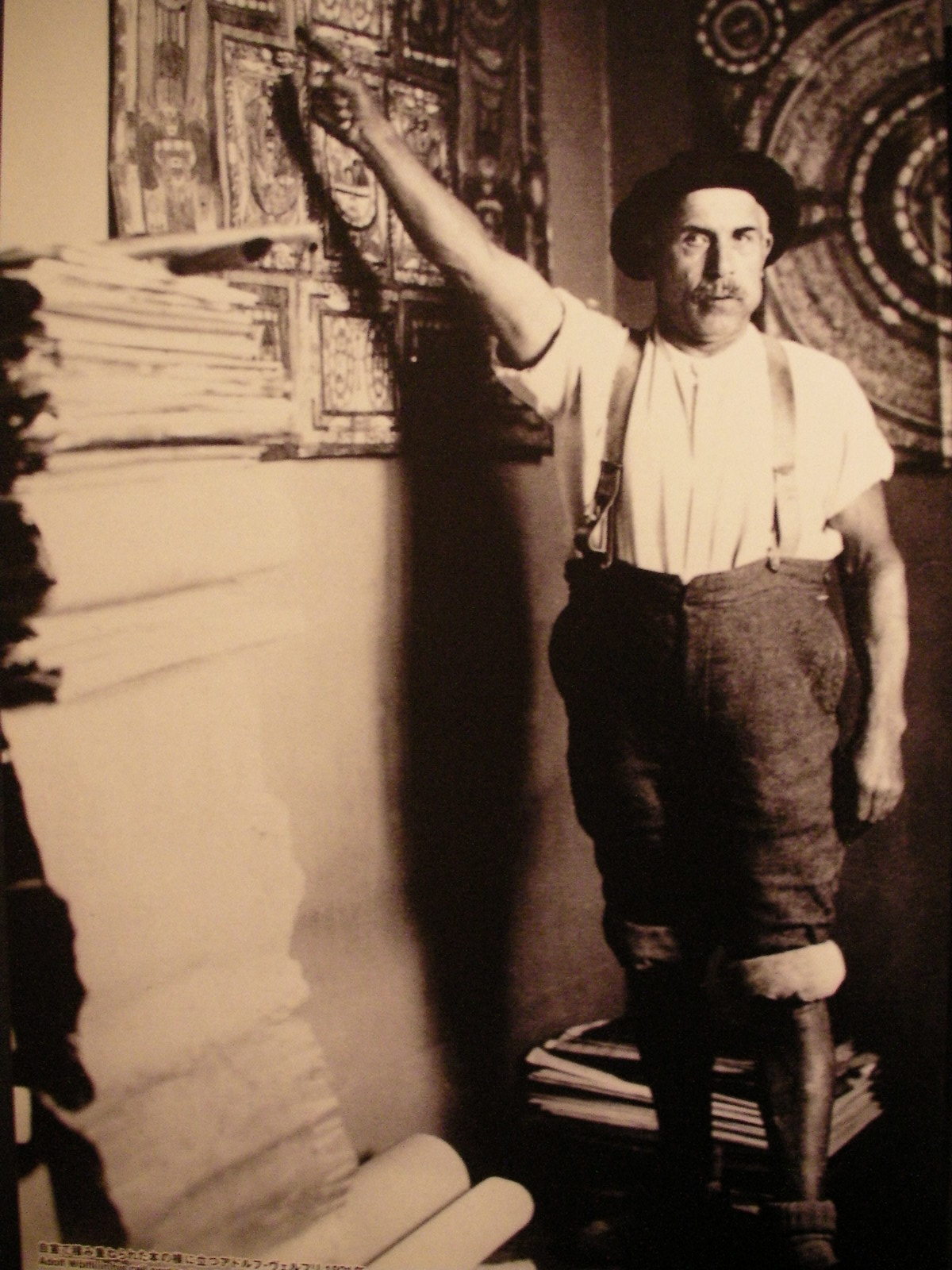 自室で積み重ねられた本の横に立つアドルフ・ヴェルフリ（1921）