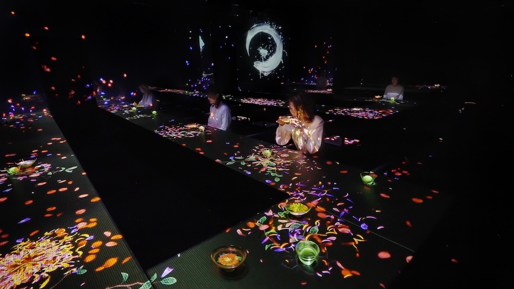 チームラボボーダレス内の「EN TEA HOUSE」の作品空間。器の中の茶に無限に広がる世界をそのまま飲むティーハウスです。チームラボ《小さきものの中にある無限の宇宙に咲く花々》、《茶の木》、《円相 - Cold Light》(C)︎ チームラボ