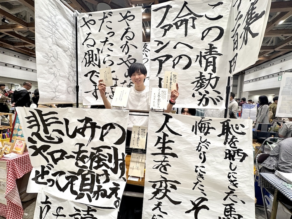 「悲しみのヤローを倒す、ぜってえ負けねえ。」のブースに立つ、詩人の涙川火水（なみだがわ ひすい）さん。カテゴリは詩歌／その他。