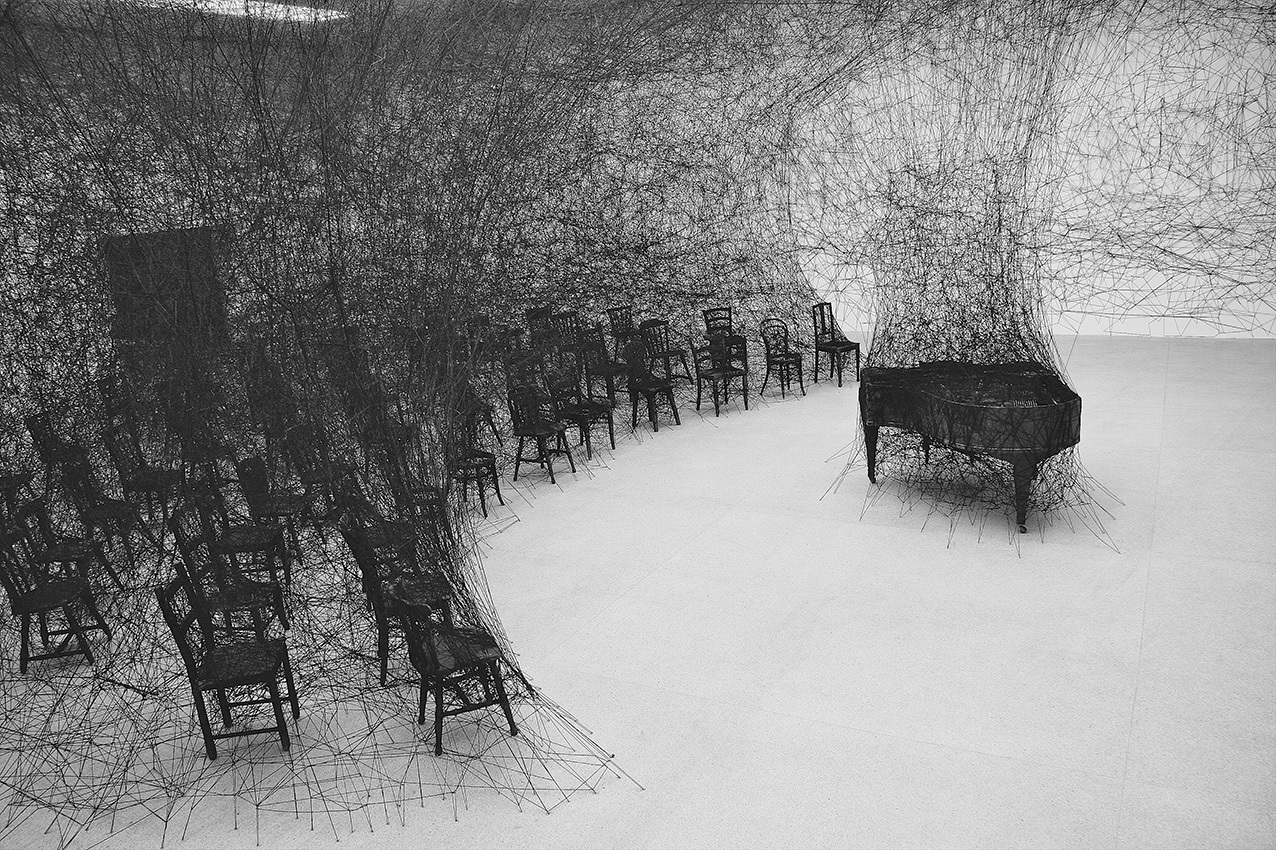 塩田千春 《静けさの中で》 2008年 焼けたピアノ、焼けた椅子、黒毛糸 展示風景：「存在様態」パスクアートセンター（ビール／ビエンヌ、スイス）2008年 撮影：Sunhi Mang