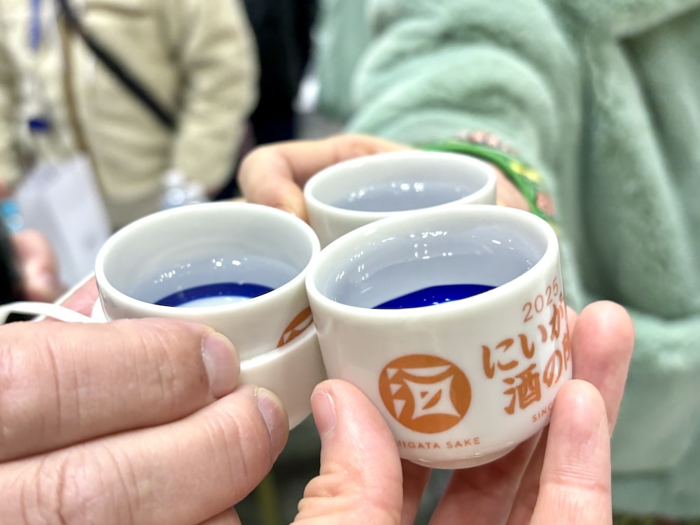 「酒の陣に乾杯！」（ちなみに左手のおちょこに装着されているシリコンカバーは、首からぶら下げられる「おちょこホルダー」。玄人の必須アイテムなのだそう）