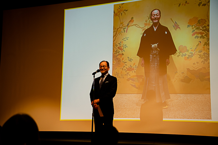 スーツ姿で登壇した井上副館長。「私も今日くらいは着物でと思いましたが、写真だけで」と断りをいれ、和装の写真を披露！